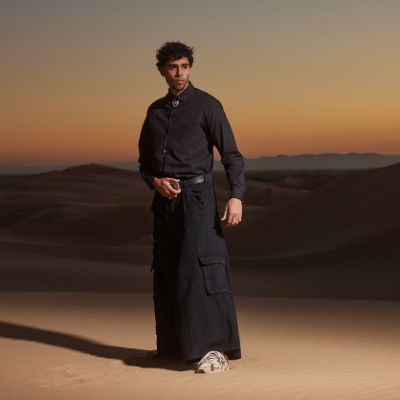 Bernie Martinez modeling for a shoot for Adidas on top sand dunes in a desert.